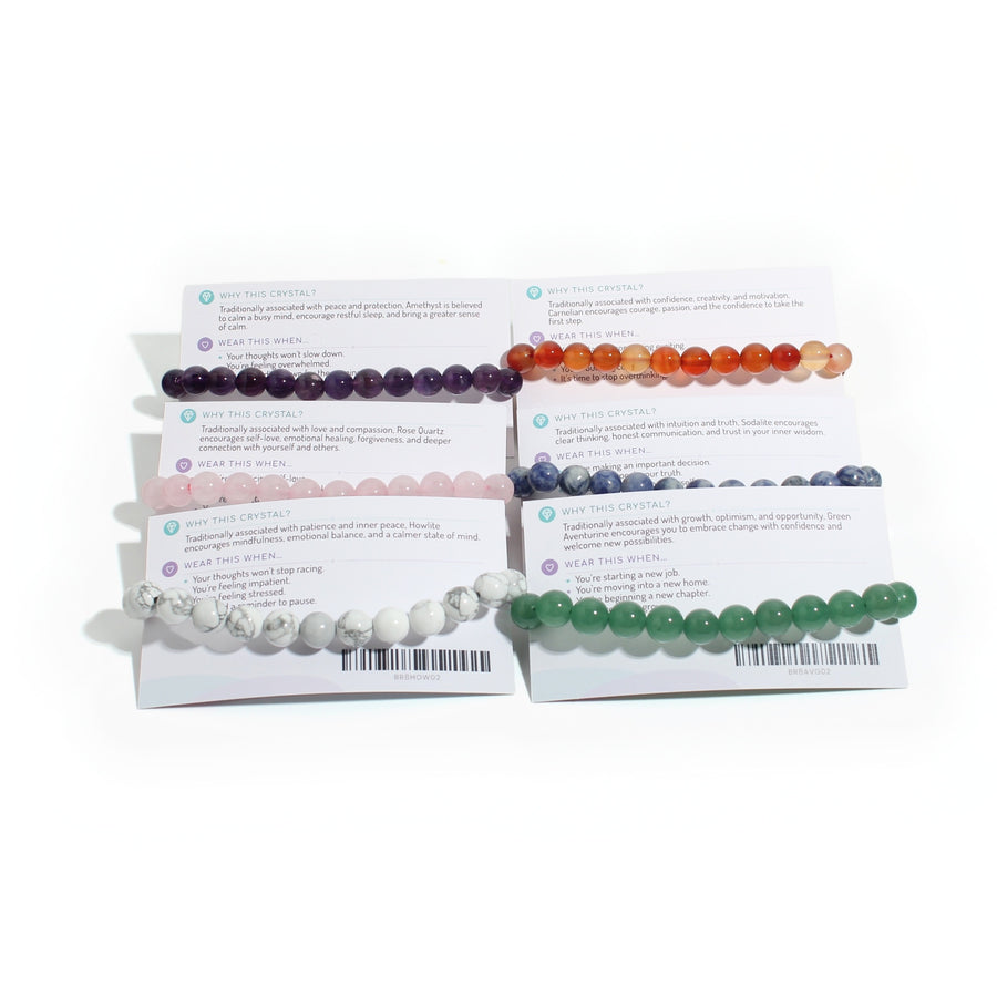 Card backs showing the Why this crystal and Wear this when text and a till barcode on each intention bracelet card, on white. Stonebridge Imports.