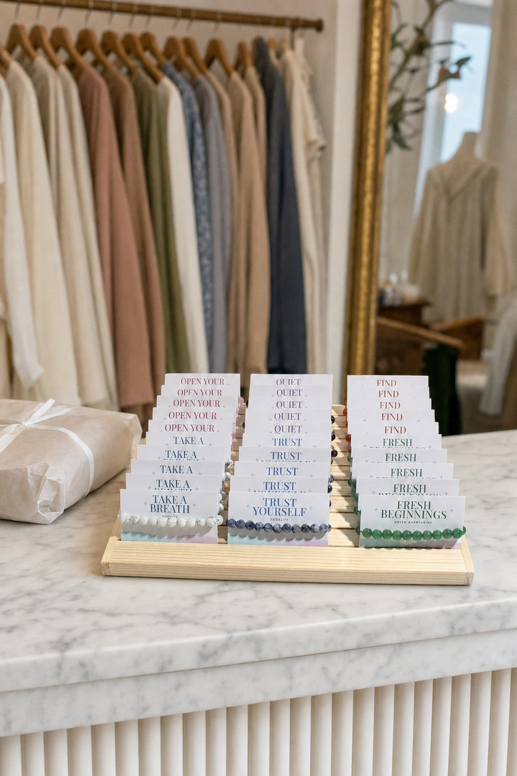 The Intention Bracelet Display Kit on the marble cash counter of a clothing boutique.