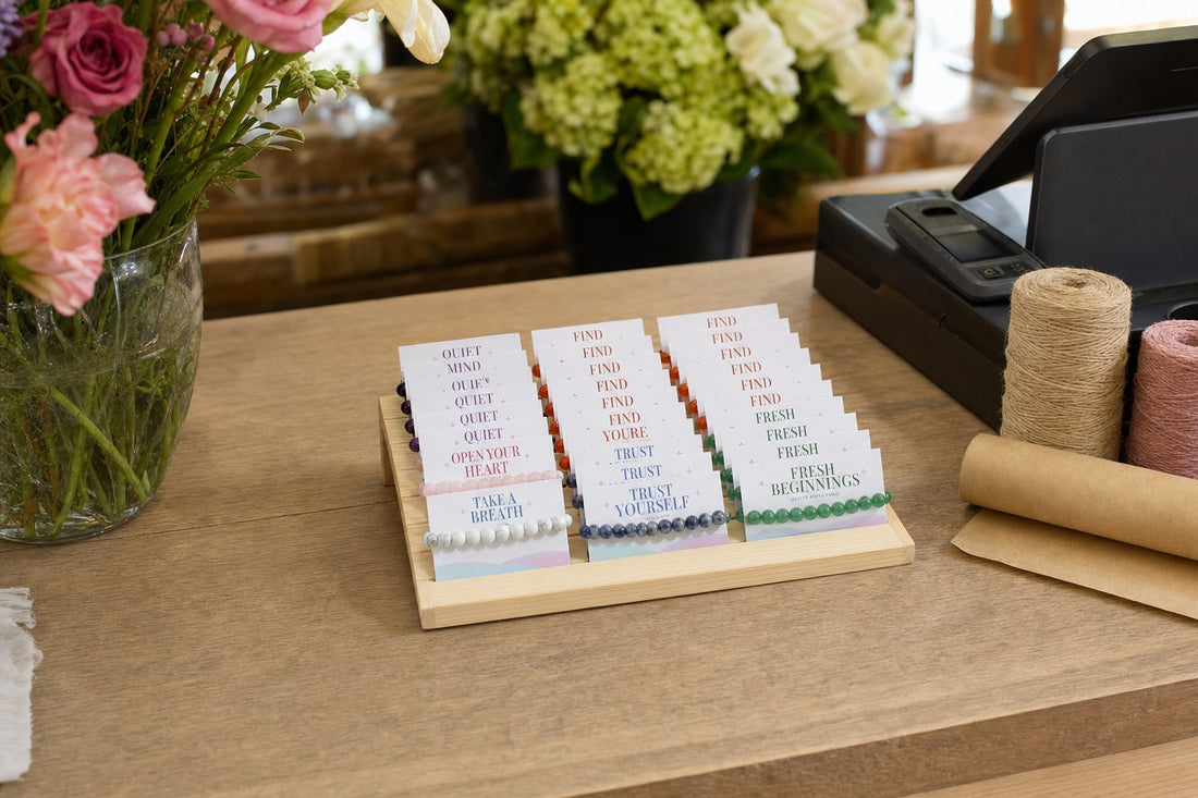 The Intention Bracelet Display Kit on a florist's counter beside the till, fresh flowers and kraft paper around it.