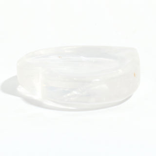 Clear Quartz Heart Bowl seen from the side, showing the shallow carved hollow and the clear quartz walls, on a clean white background. Stonebridge Imports.