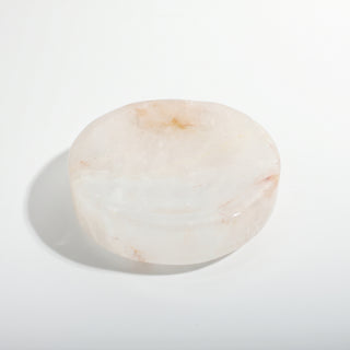 Clear Quartz Round Bowl — a small hand-carved translucent milky quartz dish with reddish iron inclusions and a shallow carved bowl, photographed on a clean white background. Stonebridge Imports.