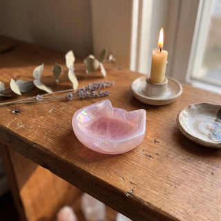 Rose Quartz Aura-Plated Cat Head Bowl displayed on a wooden home altar shelf beside a lit candle, shown at true size in warm natural light.