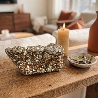 Pyrite Cluster Peru U#18 displayed on a wooden home altar shelf beside a lit candle, shown at true size in warm natural light.