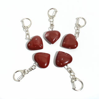Red Jasper Heart Charm - Pack of 5 - five polished deep red jasper hearts, each on its own silver-tone swivel clasp, arranged on a clean white background. Stonebridge Imports.
