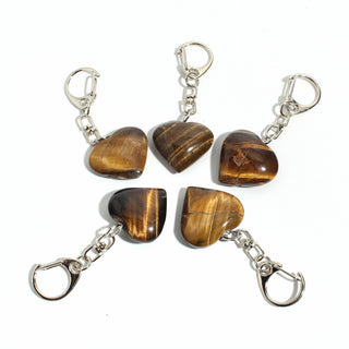 Tiger Eye Heart Charm - Pack of 5 - five polished golden-brown tiger eye hearts, each on its own silver-tone swivel clasp, arranged on a clean white background. Stonebridge Imports.