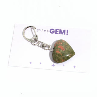 One of the five green-and-salmon unakite heart charms from the pack, shown on its "you're a GEM!" gift backing card, hanging from its silver clasp on a clean white background. Stonebridge Imports.