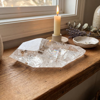Clear Quartz Free Form Unique #2 displayed on a wooden home altar shelf beside a candle, shown at true size in warm natural light.