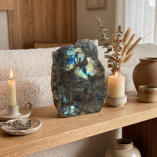 Labradorite Polished Face Cut Base Unique #2 standing on a wooden home altar shelf beside a lit candle, shown at true size in warm natural light.