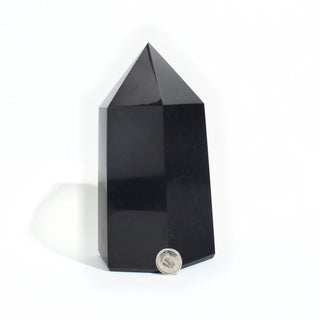 Black Obsidian Generator Unique #4 — polished six-sided tower with a faceted point, beside a Canadian dime for scale, photographed on a clean white background. Stonebridge Imports.