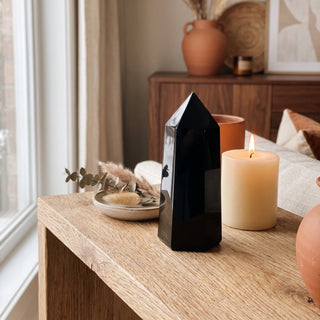 Black Obsidian Generator Unique #6 displayed on a wooden home altar shelf beside a lit candle and dried botanicals, shown at true size in warm natural light.