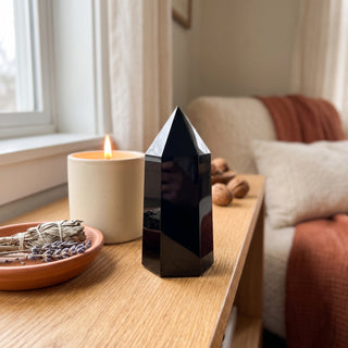 Black Obsidian Generator Unique #7 displayed on a wooden home altar shelf beside a lit candle and dried botanicals, shown at true size in warm natural light.