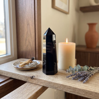 Black Obsidian Generator Unique #9 displayed on a wooden home altar shelf beside a lit candle and dried botanicals, shown at true size in warm natural light.