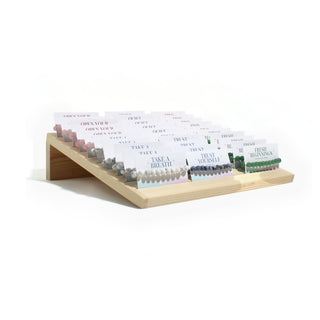 Angled view of the Intention Bracelet Display Kit showing the slanted pine stand with rows of carded 8mm stone bracelets, on white. Stonebridge Imports.