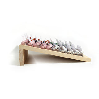Side profile of the pine counter stand showing its slope and how each carded bead bracelet sits in its slot, on white. Stonebridge Imports.