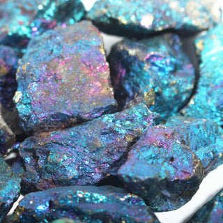 Close-up of rough chalcopyrite peacock ore chips, the iridescent teal, violet and gold film across their crystalline broken surfaces. Stonebridge Imports.