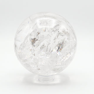Clear Quartz Sphere Unique #18 - 6 1/4", a polished clear quartz sphere on a clear display stand shown from an alternate angle on a clean white background. Stonebridge Imports.