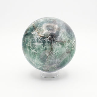 Fluorite Green and Purple Sphere Unique #11, alternate angle showing green and grey fluorite with white feathering and dark inclusions, on a clean white background. Stonebridge Imports.