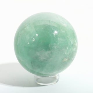 Close-up of Fluorite Green and Purple Sphere Unique #16, showing the translucent mint-green body, internal cleavage planes and white cloud-like inclusions, photographed on a clean white background. Stonebridge Imports.