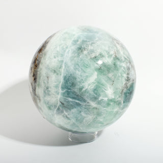 Fluorite Green and Purple Sphere Unique #9, alternate angle showing translucent sea-green fluorite with white and grey veining, on a clean white background. Stonebridge Imports.