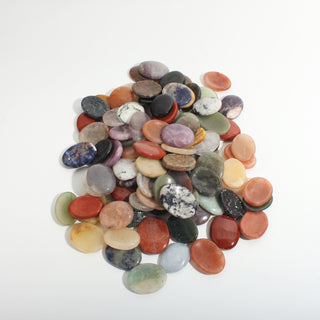 Mixed Stone Worry Stones 100-Pack — an assortment of smooth flat oval palm stones in rose quartz pink, red jasper, green aventurine, blue sodalite, amethyst and cream tones, on a clean white background. Stonebridge Imports.