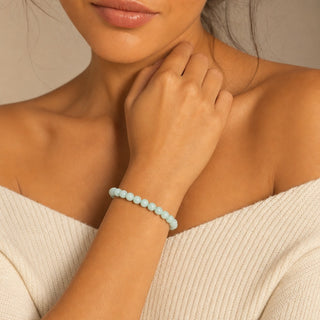 Amazonite bead bracelet worn with the fingertips resting at the collarbone