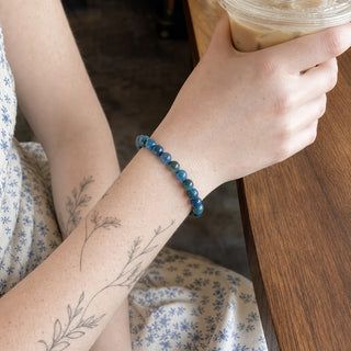 Blue Apatite bead bracelet worn on a tattooed forearm holding a coffee