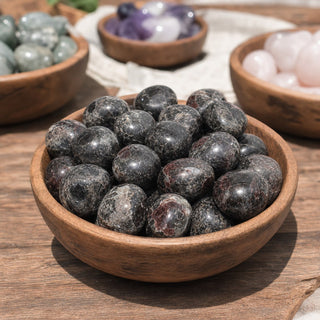 Garnet with Astrophyllite Tumbled Stones in a wooden bowl on a boutique display table