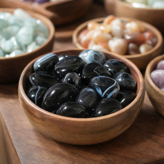 Black Banded Agate Tumbled Stones in a wooden bowl on a boutique display table