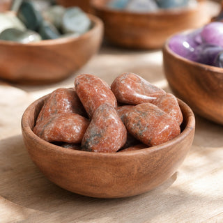 Orange Calcite Tumbled Stones - Brazil in a wooden bowl on a boutique display table