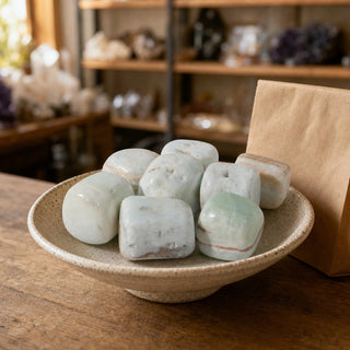 Caribbean Blue Calcite Tumbled Stones in a ceramic bowl on a shop counter