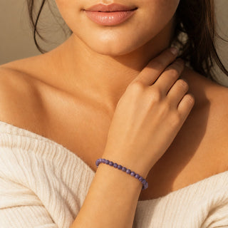 Charoite bead bracelet worn with the fingertips resting at the collarbone