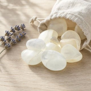 Aragonite White Tumbled Stones spilling from a linen pouch