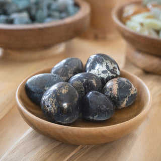 Covellite Tumbled Stones in a wooden bowl on a boutique display table