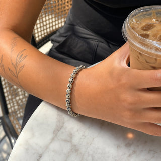 Dalmatian Jasper bead bracelet worn on a tattooed forearm holding a coffee