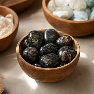 Eudialyte B Tumbled Stones in a wooden bowl on a boutique display table