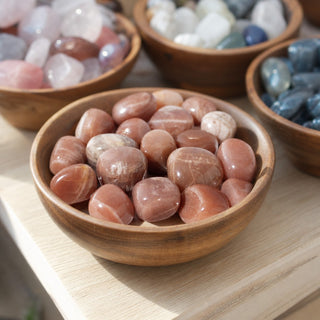 Golden Sunstone Tumbled Stones in a wooden bowl on a boutique display table