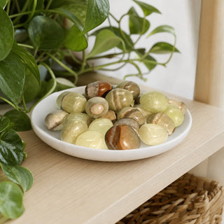 Green Aragonite Tumbled Stones in a stoneware dish on a shop shelf
