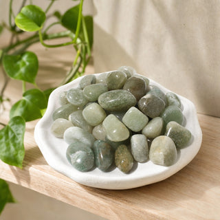 Green Aventurine Tumbled Stones - Light/Dark in a stoneware dish on a shop shelf