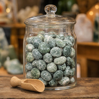 Green Spot Jasper Tumbled Stone in a glass apothecary jar with a scoop