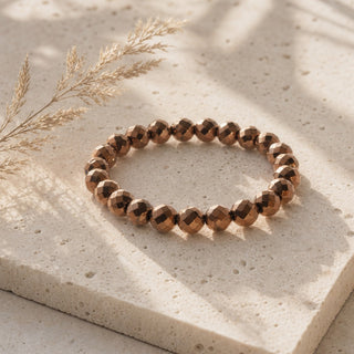 Copper Hematite, Faceted bead bracelet resting on a stone slab