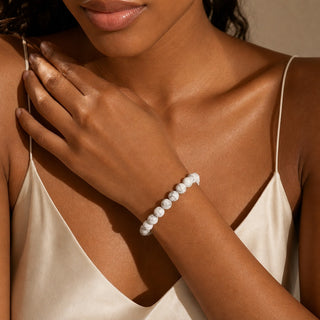 White Howlite bead bracelet worn with the hand resting on the chest