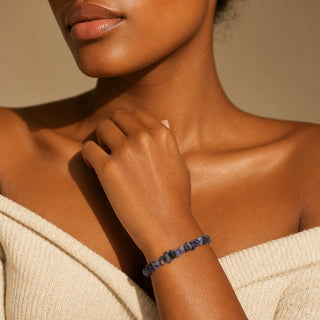 Iolite bead bracelet worn with the fingertips resting at the collarbone