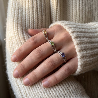 Silver Plated Adjustable Rings 3 Pack worn on a hand resting on a cream knit sweater in natural window light, showing the golden, green and violet gemstones at true scale.