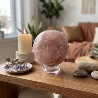 Hematoid Quartz Sphere Unique #2 - 3 3/8" displayed on a wooden home altar shelf beside a candle, shown at true size in warm natural light.