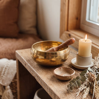 Wheel of Life Singing Bowl displayed on a wooden home altar shelf beside a candle, shown at true size in warm natural light.