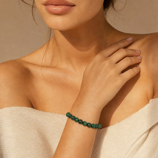 Malachite bead bracelet worn with the fingertips resting at the collarbone