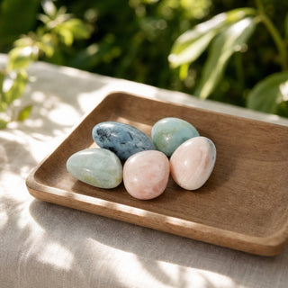 Morganite and Aquamarine Tumbled Stones in a wooden tray at a market stall