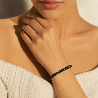 Black Obsidian bead bracelet worn with the fingertips resting at the collarbone