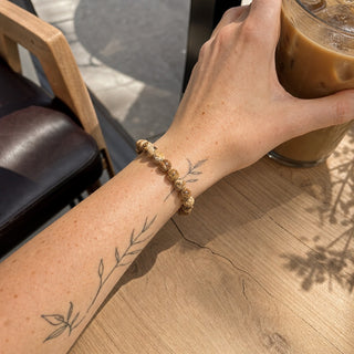 Picture Jasper bead bracelet worn on a tattooed forearm holding a coffee