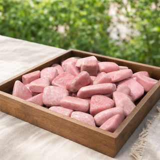 Pink Thulite Tumbled Stones in a wooden tray at a market stall